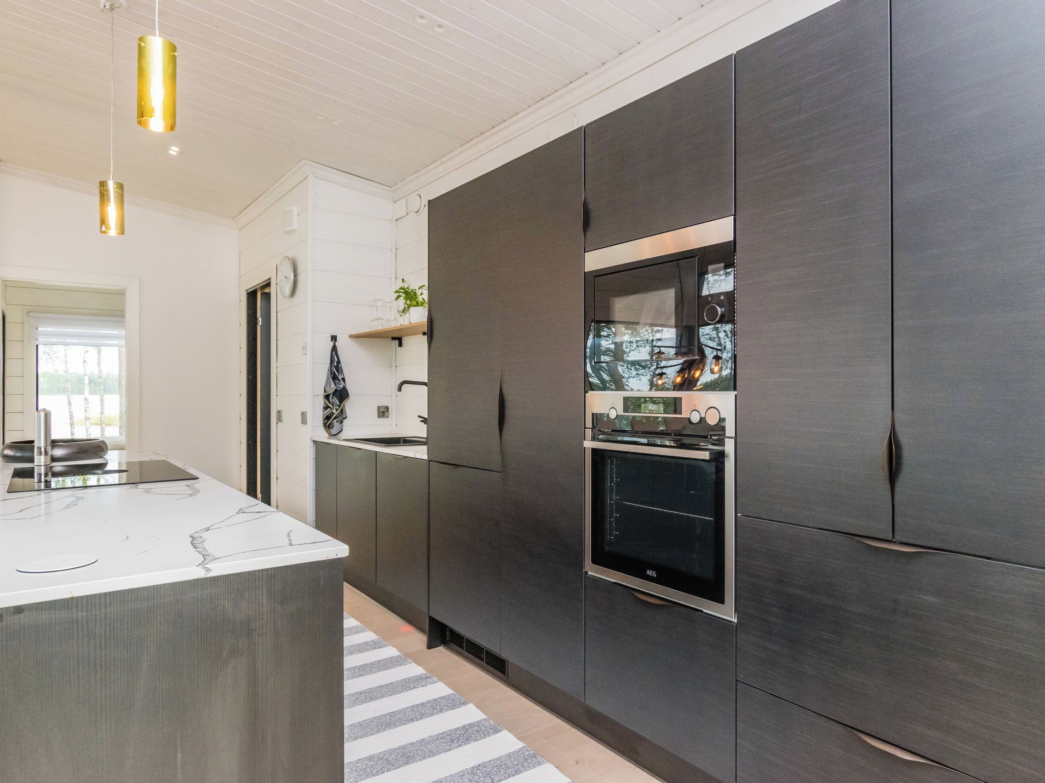 A modern kitchen with dark cabinetry, a central island, and pendant lighting.