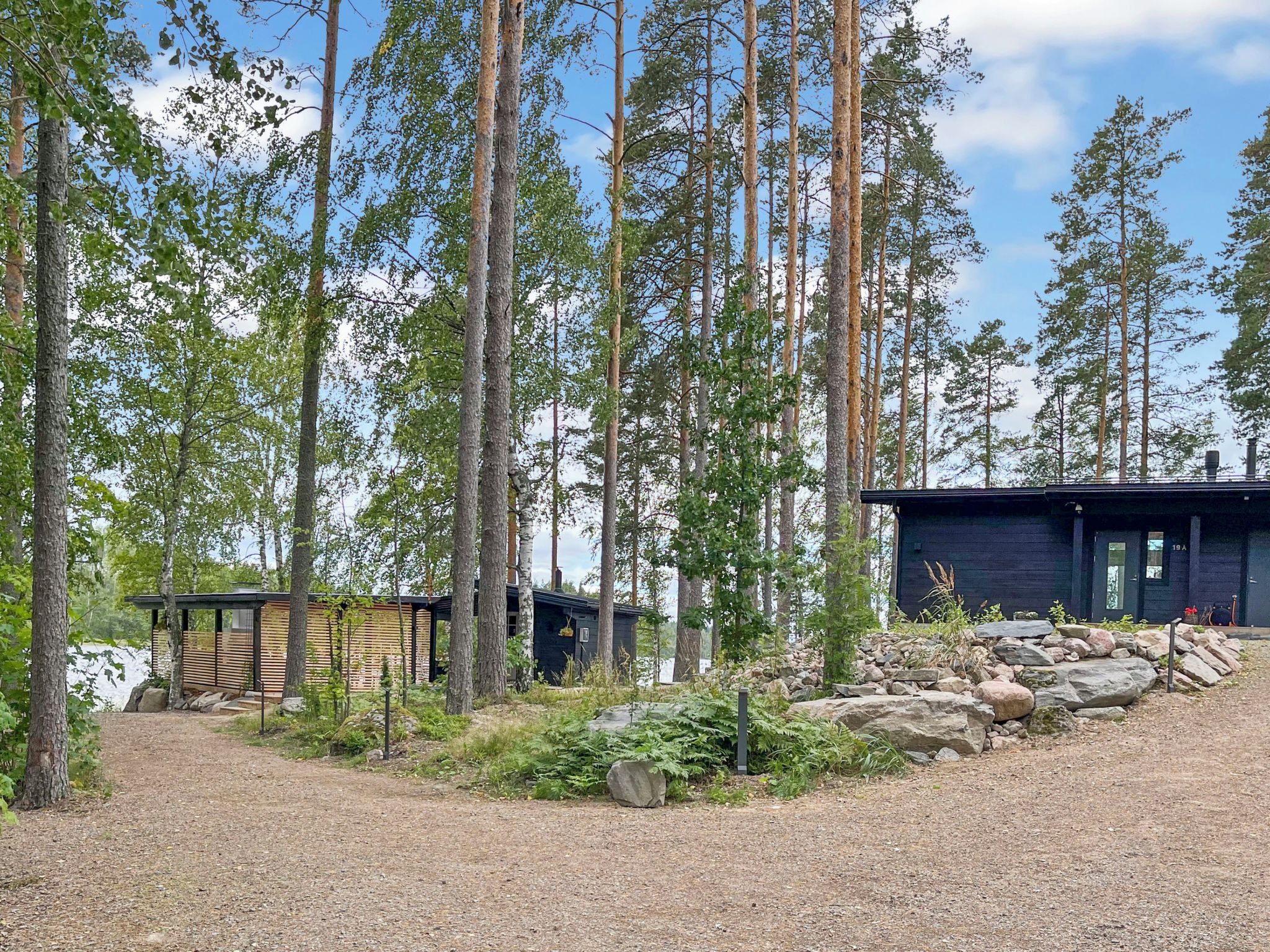 A cabin surrounded by tall trees, with a gravel path leading to it.