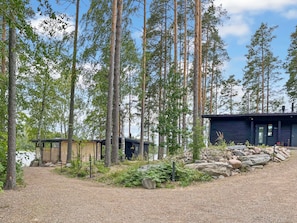 Une cabane entourée de grands arbres, avec un chemin de gravier menant à celle-ci.