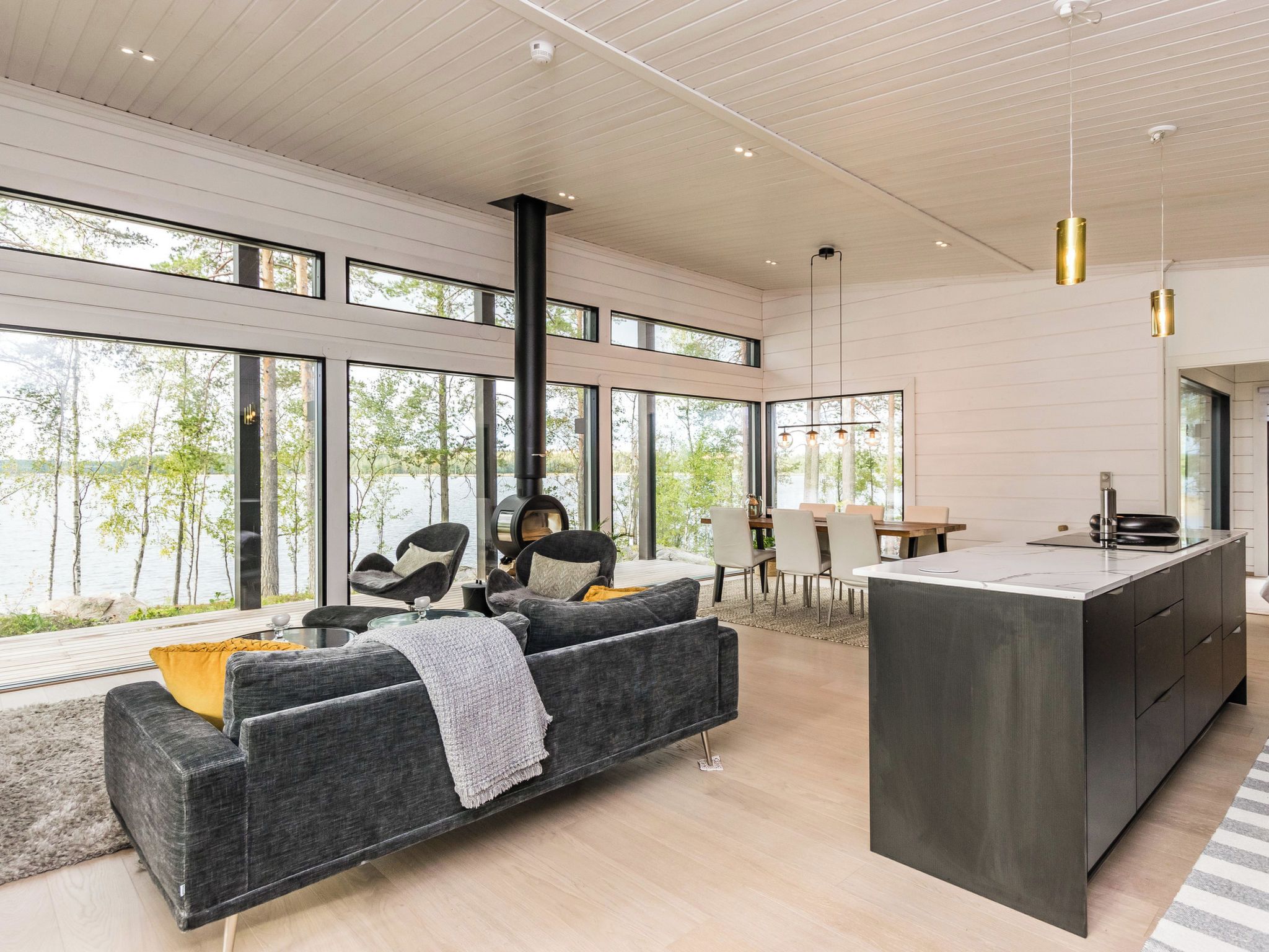 Un interior moderno con sofá, zona de comedor y isla de cocina.