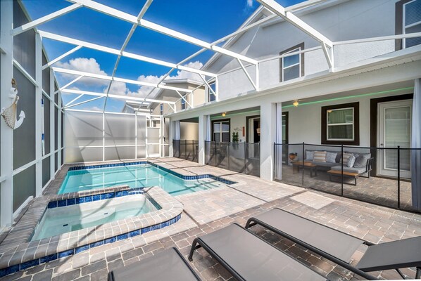 A covered outdoor swimming pool with lounge chairs and a patio area.
