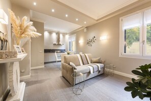 A modern living room with a sofa, a dining area, and a kitchen in the background.