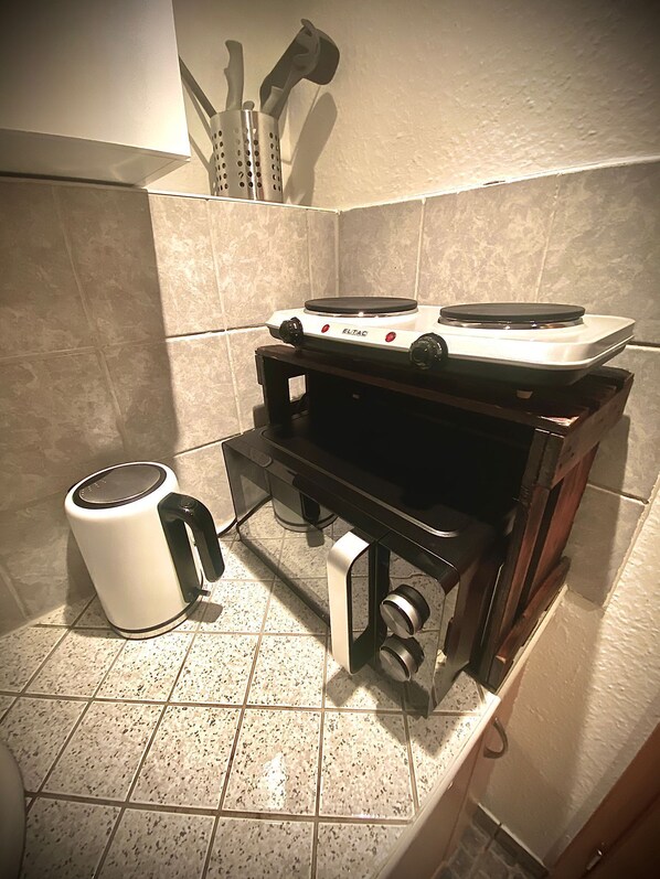 A compact kitchen with a gas stove, a kettle, and a sink.