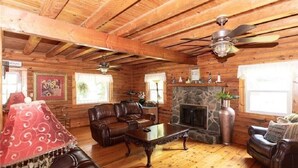A log cabin interior with a stone fireplace, leather sofas, and a wooden ceiling. - Welcome to Holly Hill – peaceful lakefront living (Denver)