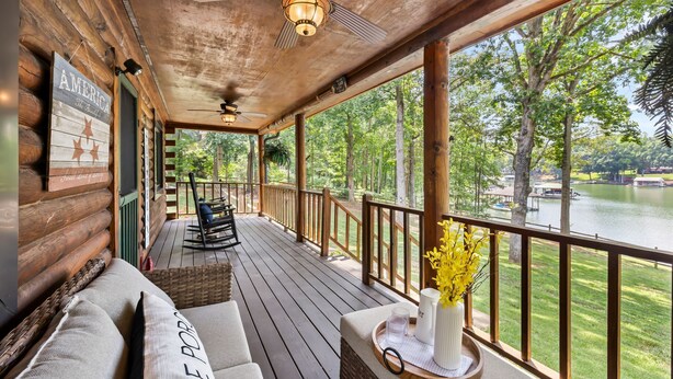 A wooden deck with a sofa, a fan, and a view of a lake. - Welcome to Holly Hill – peaceful lakefront living (Denver)