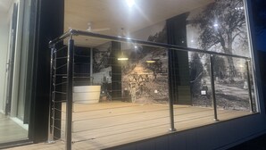 Un edificio moderno con fachada de vidrio, barandilla de metal y vistas a un paisaje montañoso.