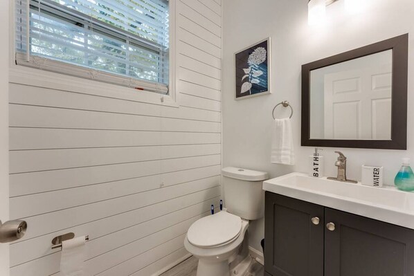 A bathroom with a toilet, sink, and mirror.
