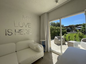 A modern bedroom with a white sofa, a large bed, and a statement wall with 'MY LOVE IS HERE' letters. - Beautiful apartment in villa for 8 guests with A/C, pool, TV and terrace (San Teodoro)