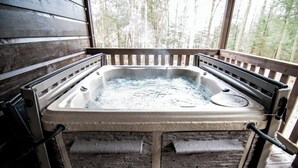 Un jacuzzi en una cabaña de madera con vistas a árboles.