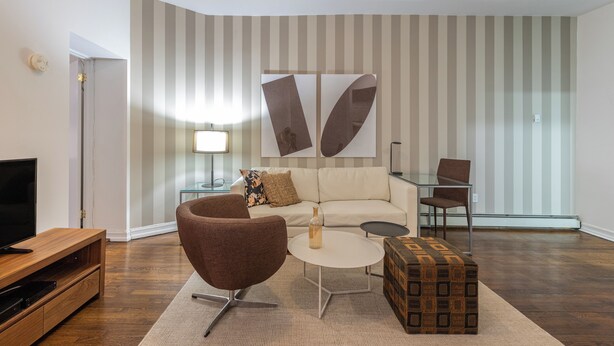 Un salon moderne comprenant un canapé, un fauteuil, une table basse et un meuble pour la télévision.