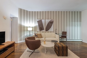 Una sala moderna con sofá, sillón, mesa de centro y mueble para televisión.