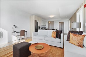 A modern living room with a white sofa, a coffee table, and a dining area with a chair and table.