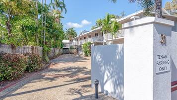 A gated driveway with a 'Tenant Parking Only' sign, surrounded by lush greenery and a clear blue sky.