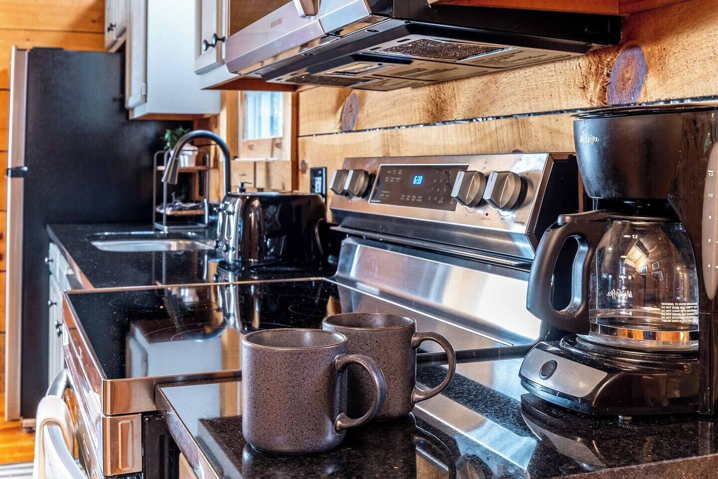 A modern kitchen with stainless steel appliances, including a stove, oven, and coffee maker.