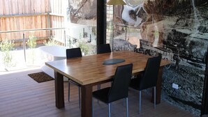 Ein Essbereich mit einem Holztisch, schwarzen Stühlen und einer Glaswand mit Wandgemälde.