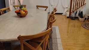 A dining area with a round table, wooden chairs, a fruit bowl, and a staircase leading to another level.