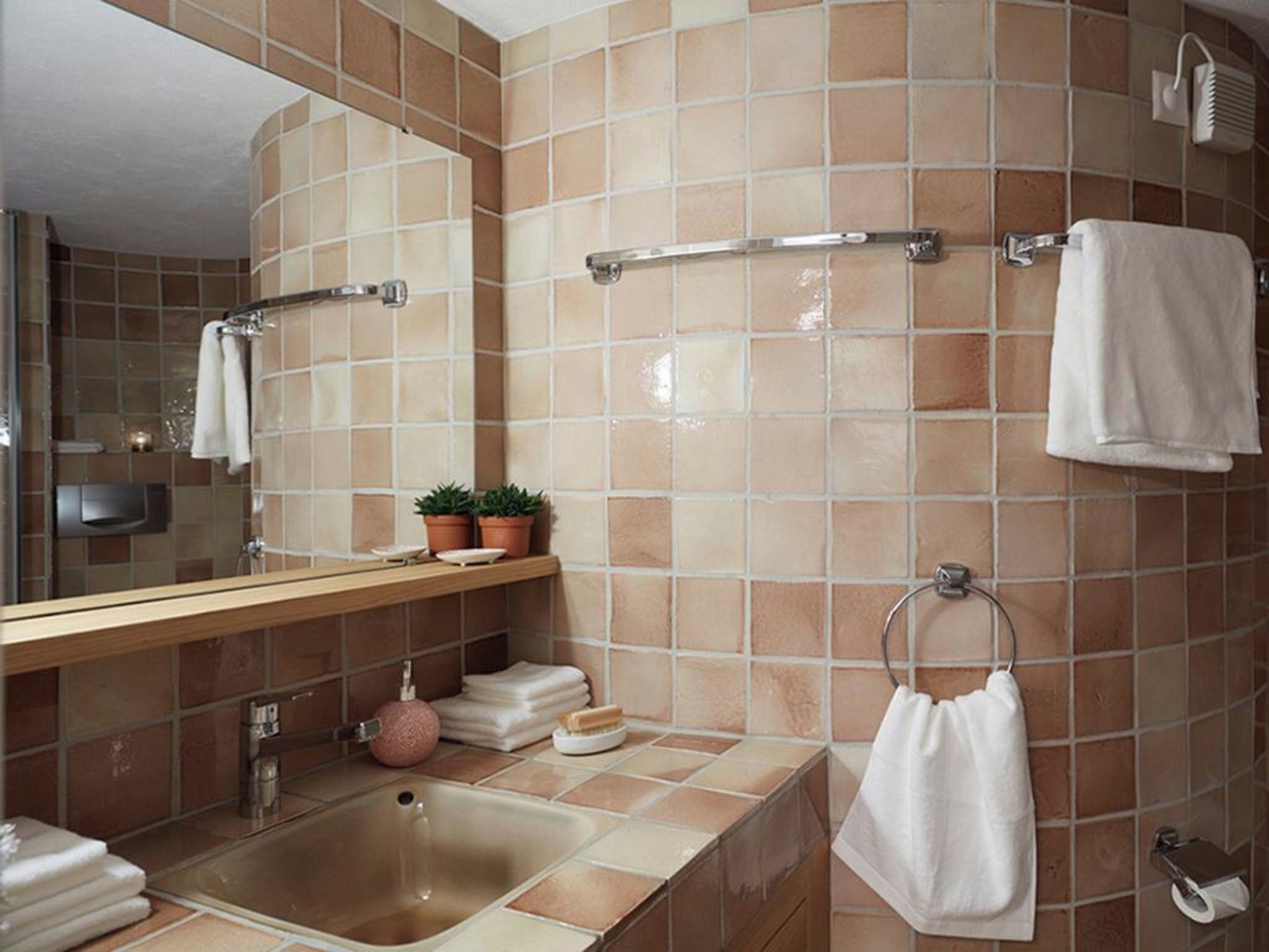 Un baño con lavamanos, espejo, toallero y zona de ducha.