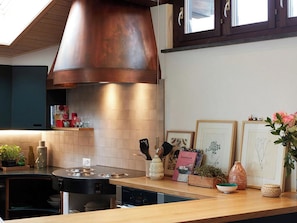 A modern kitchen with a stainless steel cooktop, a built-in oven, and a copper range hood. - Am Dürrbach 2/244 Appartement/Fewo 6-Bettwohnung by Interhome (Engelberg)