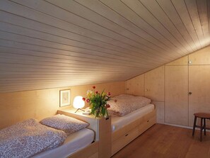 A small, cozy bedroom with two beds, a nightstand, a lamp, and a wooden wardrobe. - Am Dürrbach 2/244 Appartement/Fewo 6-Bettwohnung by Interhome (Engelberg)