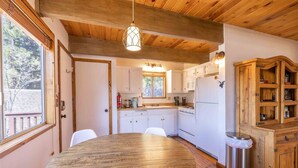 Una cocina con armarios de madera, una mesa redonda de madera y un colgador de luz.