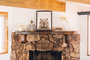 A stone fireplace with a framed bear picture, candles, and decorative items on the mantel. - Serene mountain escape near Big Bear Village, Hiking Trails, and Zoo! (Big Bear Lake)