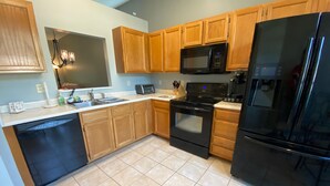 A kitchen with wooden cabinets, a black refrigerator, a microwave, and a stove. - Quiet 3BR Home near IU Campus - Perfect for Game Days, Lotus, Events & Families (Bloomington)