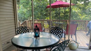 A glass table with chairs on a deck, a red umbrella, and a lantern. - Quiet 3BR Home near IU Campus - Perfect for Game Days, Lotus, Events & Families (Bloomington)