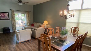 A dining area with a glass-top table, wooden chairs, and a chandelier. - Quiet 3BR Home near IU Campus - Perfect for Game Days, Lotus, Events & Families (Bloomington)