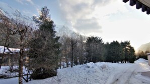 Un paysage enneigé avec un ciel dégagé, des arbres et une route.