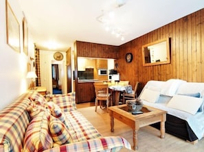 A cozy living room with a plaid sofa, a wooden coffee table, and a white couch.