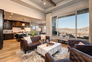 Upper level living room with leather furnishings, smart TV, gas fireplace, reading bench, and views of the surrounding area and mountains