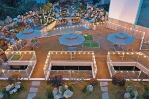 An outdoor patio area with seating, a water feature, and a fenced play area.