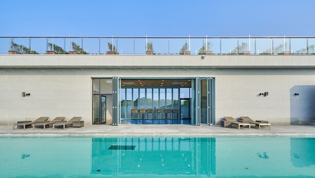A swimming pool with lounge chairs and a glass door entrance. - JN Park Hotel (Incheon)