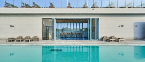 Una piscina al aire libre, sillones reclinables de piscina