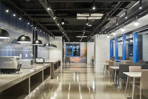Un espacio interior moderno con una larga barra, una zona de estar y un mural en la pared.