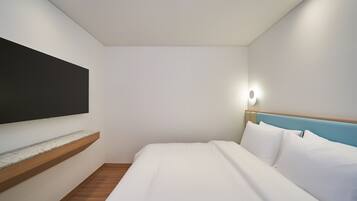 A modern hotel room with a bed, a mounted TV, and a nightstand.