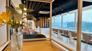A modern interior with a large window, a wooden table, and a seating area. - JN Park Hotel (Incheon)