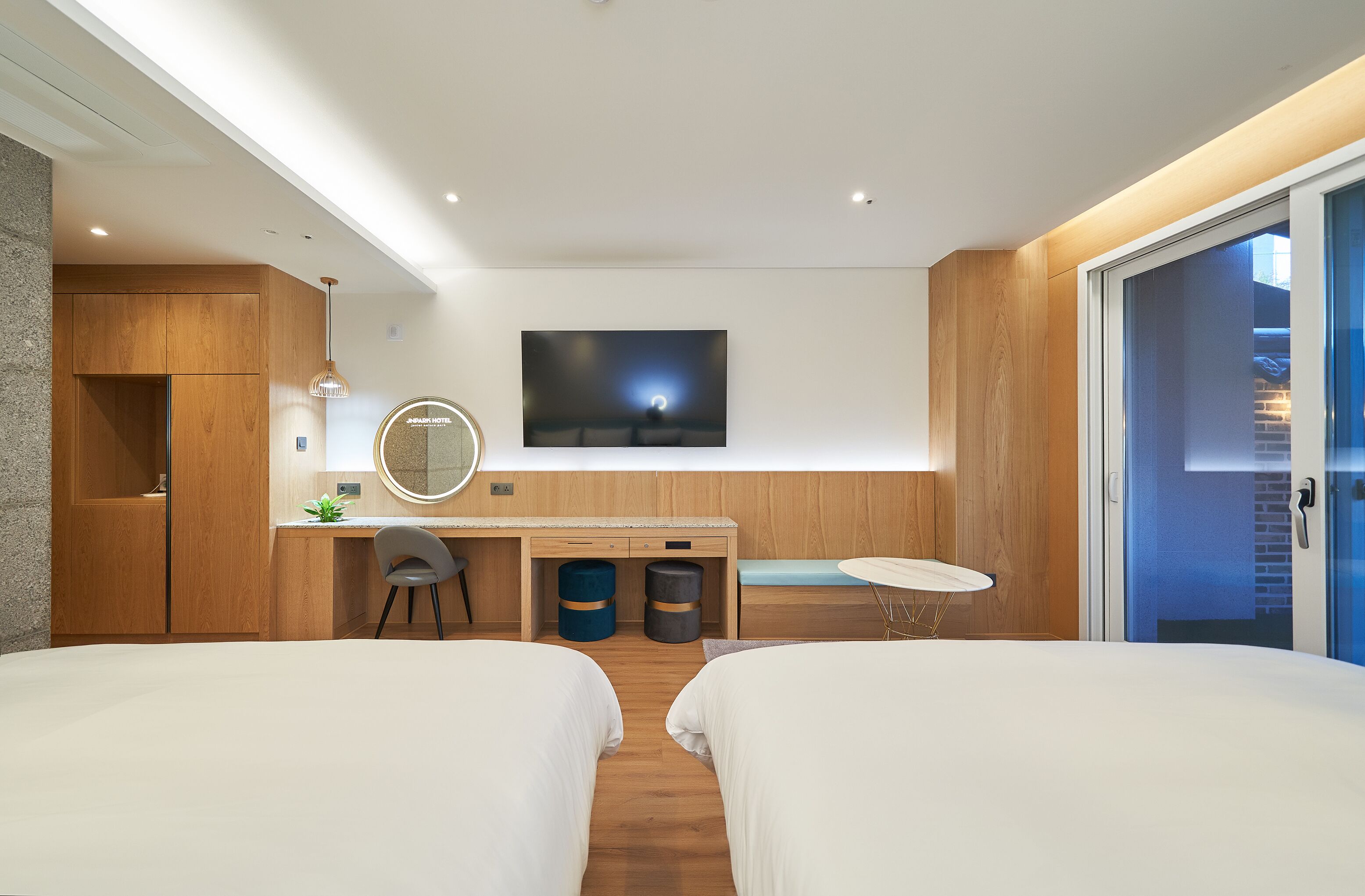 Una habitación de hotel moderna con dos camas, un escritorio, un televisor y una pequeña zona de estar.