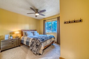 A bedroom with a bed, nightstand, lamp, and a ceiling fan.
