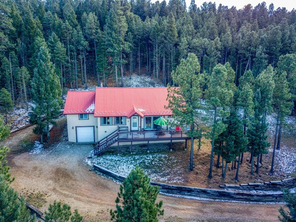 A two-story house with a red roof, a covered porch, and a gravel driveway.