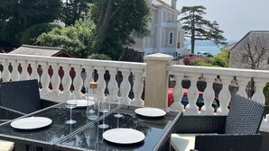 Un área de comedor al aire libre con una mesa de vidrio, platos blancos y copas de vino.