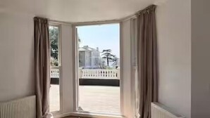 Una habitación con un ventanal grande, un radiador y una cama.