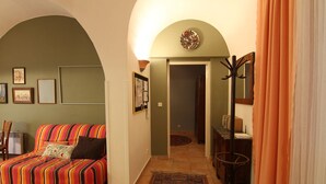 Un salon chaleureux avec un canapé à rayures, un petit tapis et un porte-manteau.