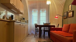 Une cuisine de taille réduite avec une table et des chaises, un canapé rouge et un lustre.