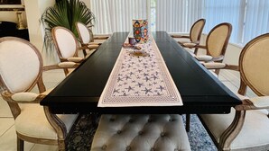 Un comedor con una mesa larga, sillas tapizadas y un corredor con estampado.