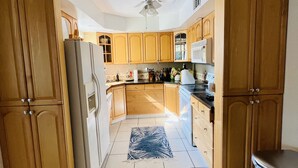 Una cocina con armarios de madera, un refrigerador, un microondas y un ventilador de techo.