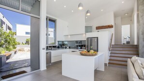 Una cocina moderna con una isla central, horno empotrado y refrigerador de acero inoxidable.