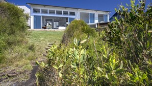 Una casa moderna de dos plantas con un amplio porche delantero, un garaje a la vista y un césped bien cuidado.