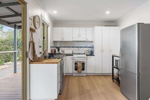 Una cocina moderna con armarios blancos, un refrigerador de acero inoxidable y una encimera de madera.