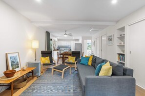 Una sala de estar moderna con un sofá, sillas, una mesa de centro y un comedor al fondo.